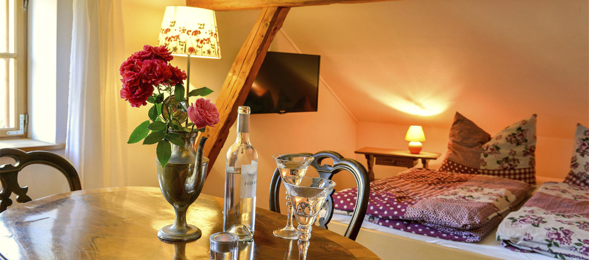 Die Kunstgalerie - Blick auf Tisch und Bett - Dekoration und TV