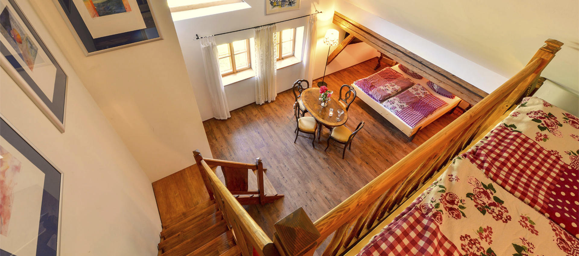 Die Kunstgalerie - Blick von der Galerie hinunter auf Tisch und Bett